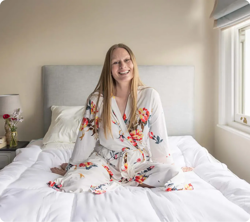 Woman sitting up in a bright, comfortable bed