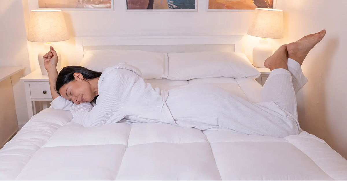 Woman stretching awake on a CloudTopper-covered bed