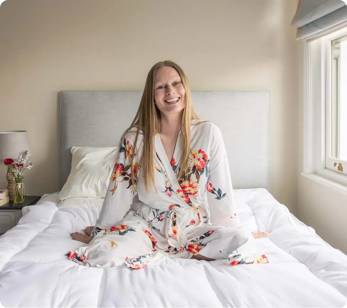 Woman sitting up in a bright, comfortable bed