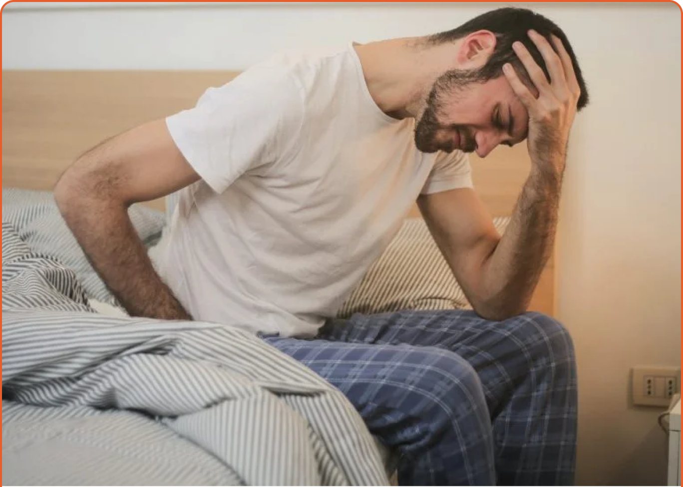 Man sitting on the edge of the bed holding his head